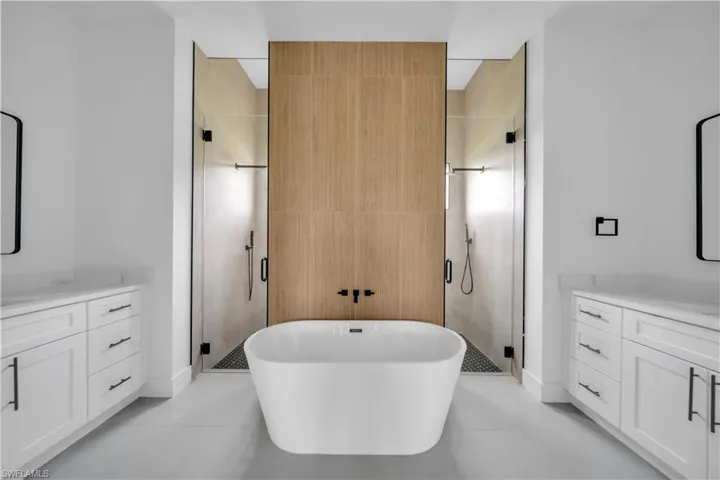 Full bath with vanity, a shower stall, a freestanding tub, tile walls, and light tile patterned flooring