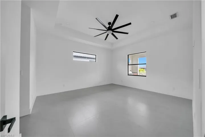 Spare room featuring a raised ceiling and ceiling fan