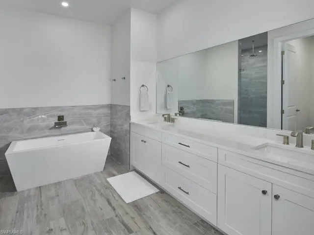 Primary Bathroom with double vanity, a freestanding soaking tub, and walk-in shower
