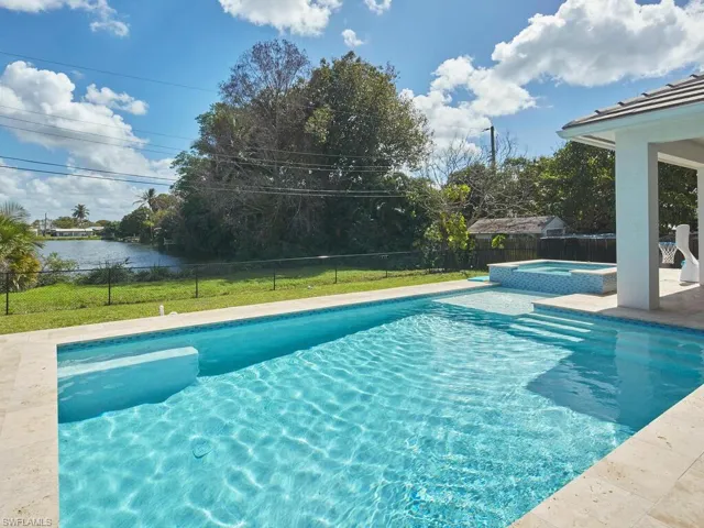 Beautiful pool with sun shelf, steps, and integrated spa overlooking lake