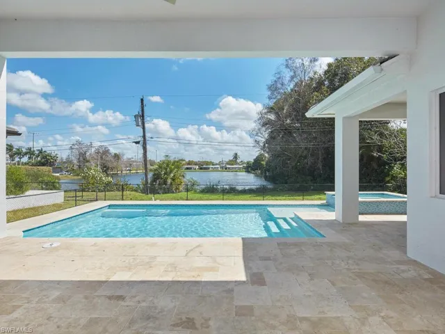 Covered lanai with paver pool deck, a fenced backyard, and lake views