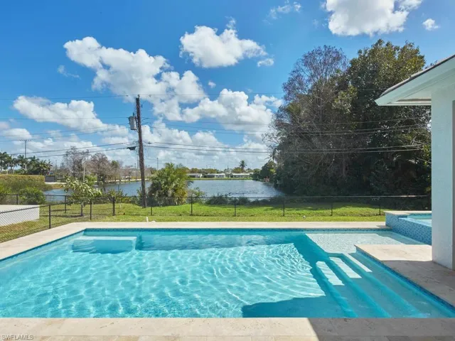 Beautiful pool with sun shelf, steps, and integrated spa overlooking lake