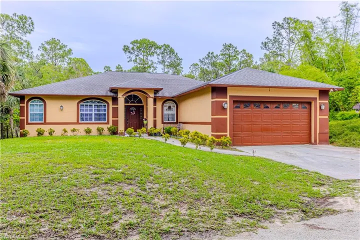 Ranch-style home with stucco siding, an attached garage, a front yard, concrete driveway, and a shingled roof
