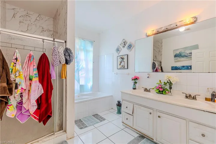 Bathroom featuring tile patterned floors, a garden tub, double vanity, a shower stall, and tile walls