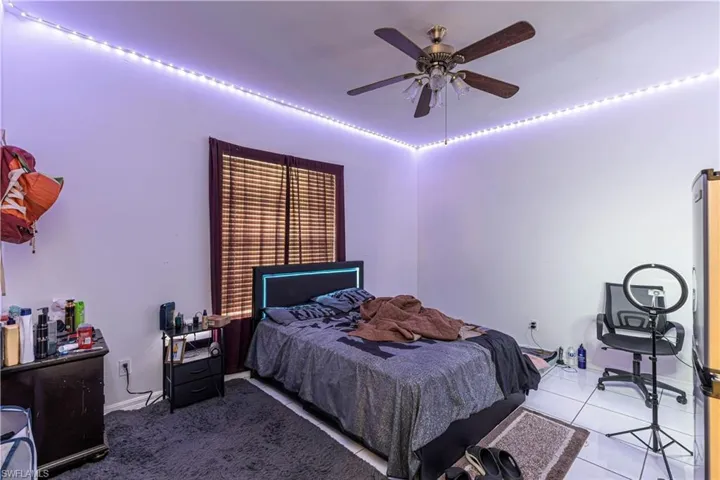 Tiled bedroom with ceiling fan and baseboards