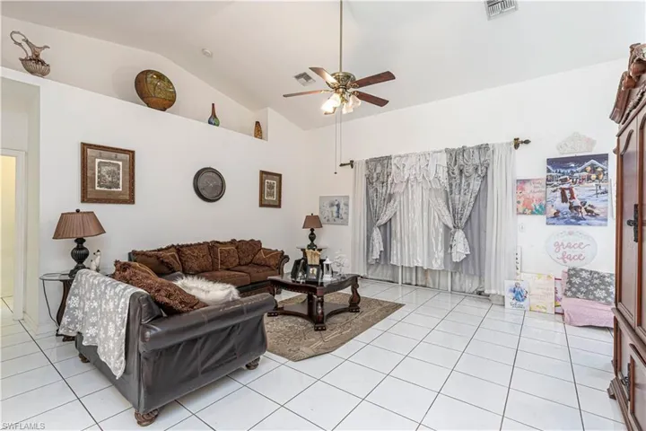 Living area featuring light tile patterned floors, ceiling fan, and high vaulted ceiling