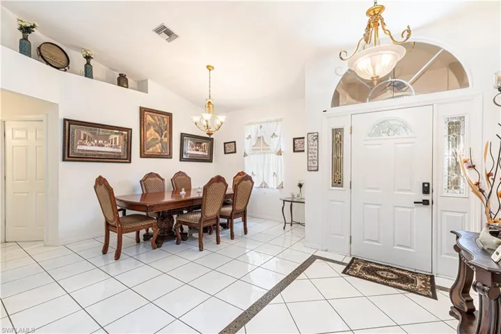Dining room featuring a chandelier, vaulted ceiling, baseboards, and light tile patterned floors
