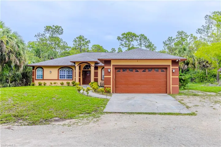 Ranch-style house with concrete driveway, stucco siding, a front yard, and an attached garage
