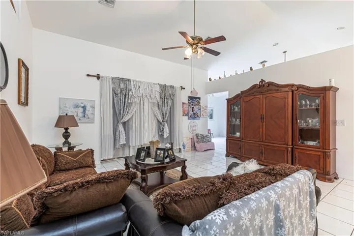 Living room featuring light tile patterned flooring, a ceiling fan, and vaulted ceiling