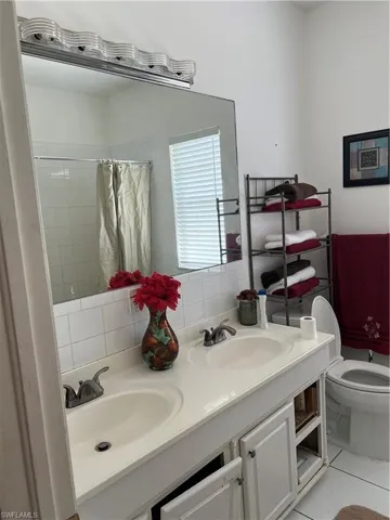 Bathroom with double vanity, curtained shower, and tile patterned floors