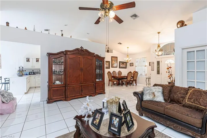 Living room featuring a ceiling fan, light tile patterned floors, a chandelier, and high vaulted ceiling
