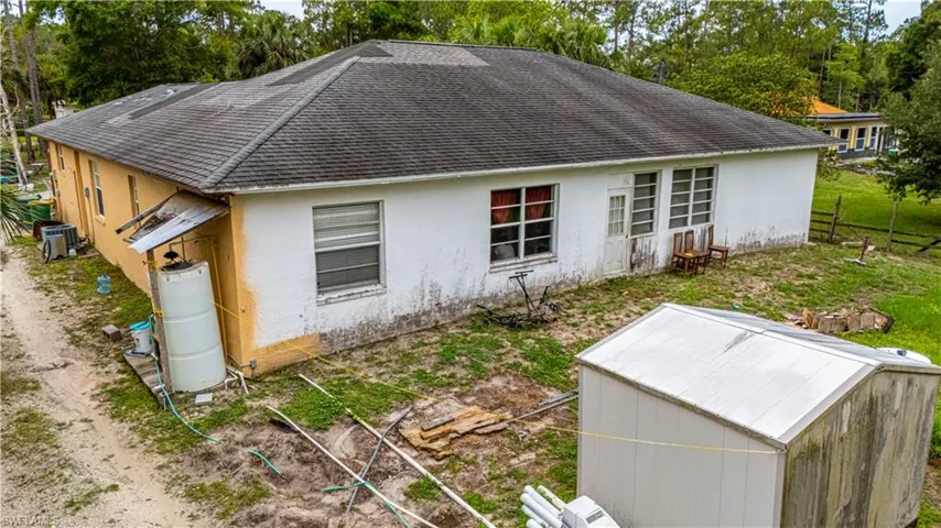 Back of property featuring stucco siding, roof with shingles, and view of scattered trees
