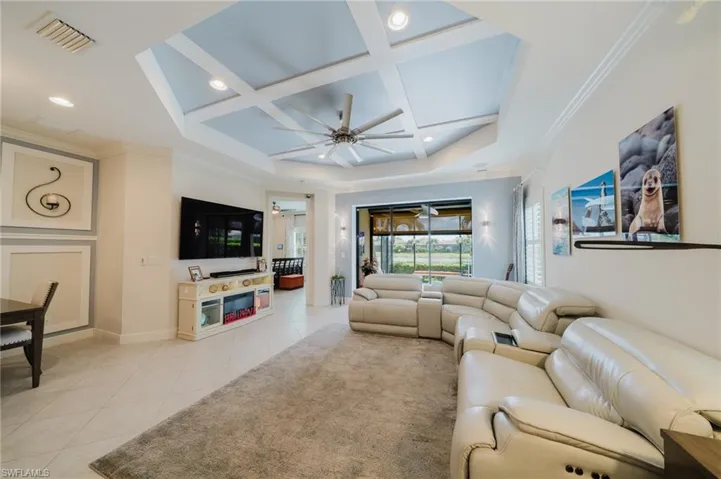 Living room with crown molding, coffered ceiling, light tile patterned floors, ceiling fan, and recessed lighting