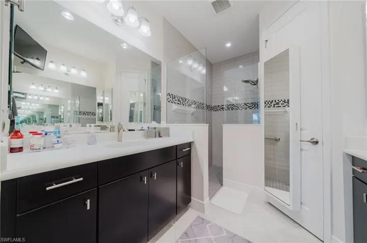 Bathroom with light tile patterned floors, vanity, and a walk in shower