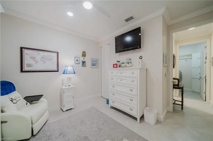 Living area with ornamental molding, light tile patterned floors, and ceiling fan