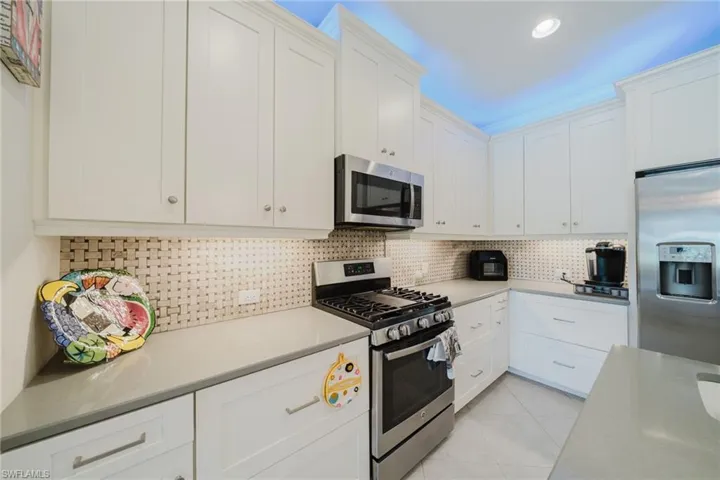 Kitchen featuring stainless steel appliances, white cabinetry, tasteful backsplash, light tile patterned floors, and recessed lighting