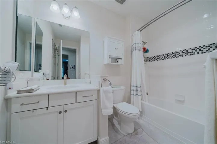 Full bath featuring shower / bath combo with shower curtain, vanity, and light tile patterned flooring