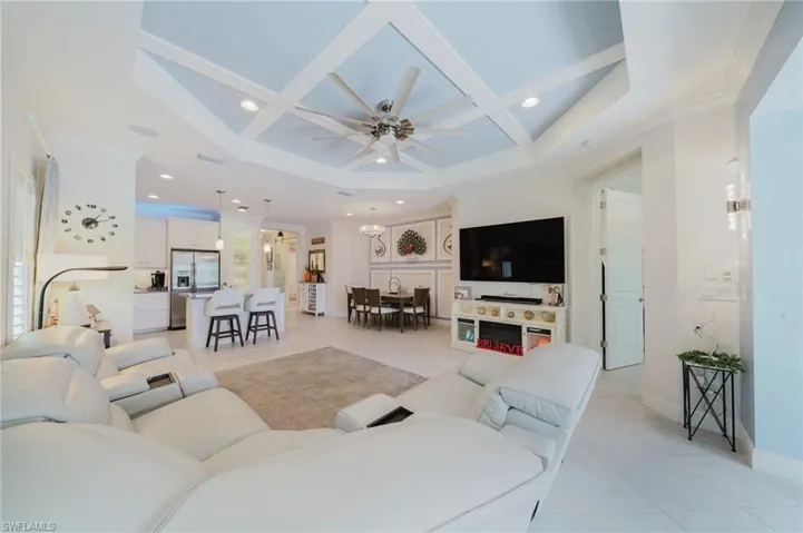 Living room with light tile patterned flooring, coffered ceiling, a ceiling fan, recessed lighting, and ornamental molding