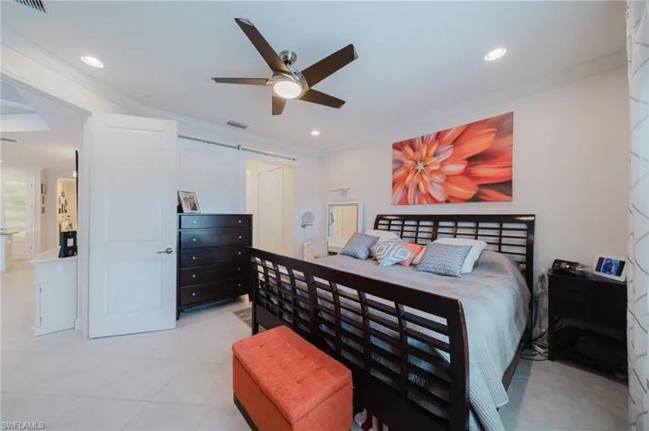 Bedroom featuring ornamental molding, light tile patterned floors, a barn door, ceiling fan, and recessed lighting