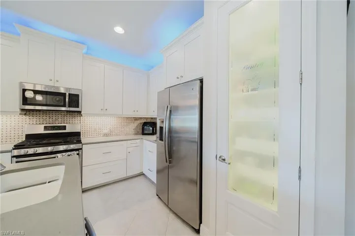 Kitchen featuring white cabinets, stainless steel appliances, tasteful backsplash, light tile patterned floors, and recessed lighting