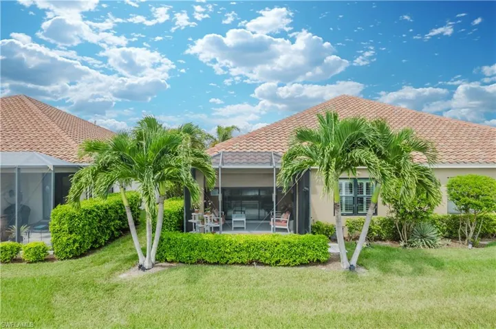 Back of property with glass enclosure, a sunroom, and a lawn