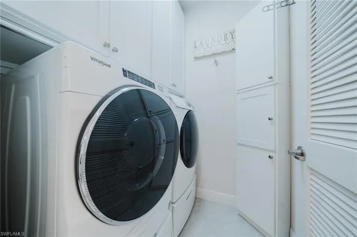 Washroom with separate washer and dryer, light tile patterned flooring, and cabinet space