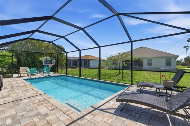 Swimming pool featuring a lawn, glass enclosure, and a sunroom