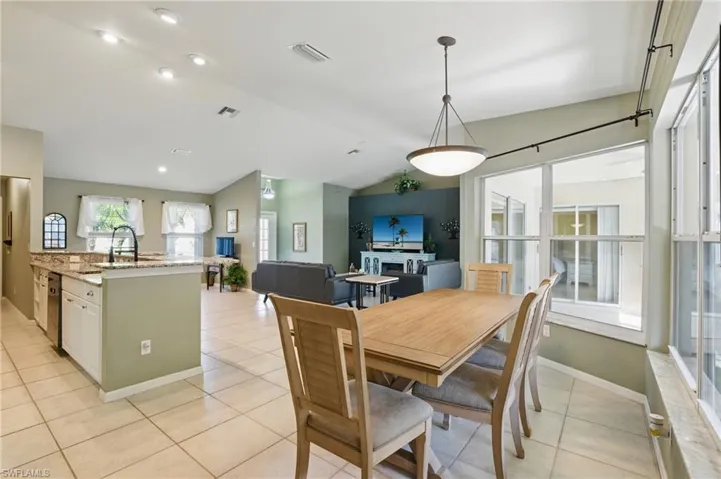 Dining area featuring light tile patterned floors, visible vents, lofted ceiling, and baseboards