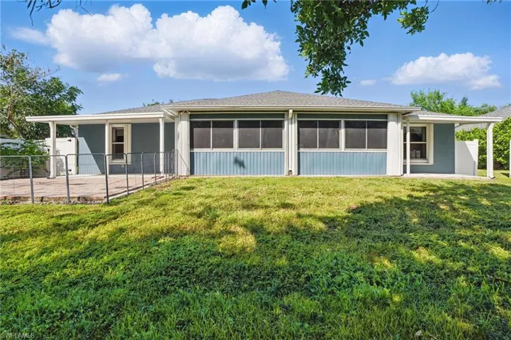 Back of property with a yard, fence, stucco siding, and a sunroom