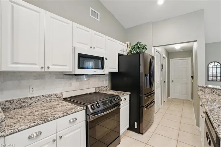 Kitchen with visible vents, black electric range oven, tasteful backsplash, white microwave, and dishwasher