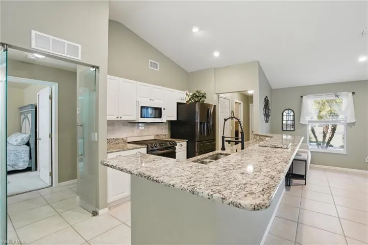Kitchen with white microwave, visible vents, electric range oven, light tile patterned floors, and a sink