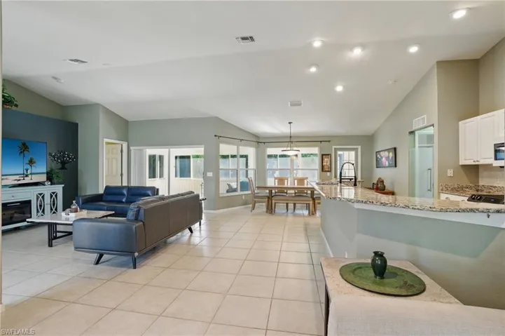 Living room with light tile patterned floors, visible vents, and vaulted ceiling