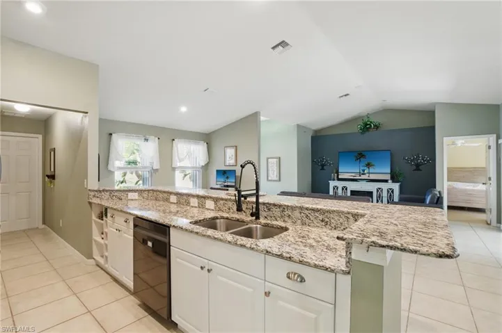 Kitchen featuring light tile patterned flooring, visible vents, black dishwasher, and a sink