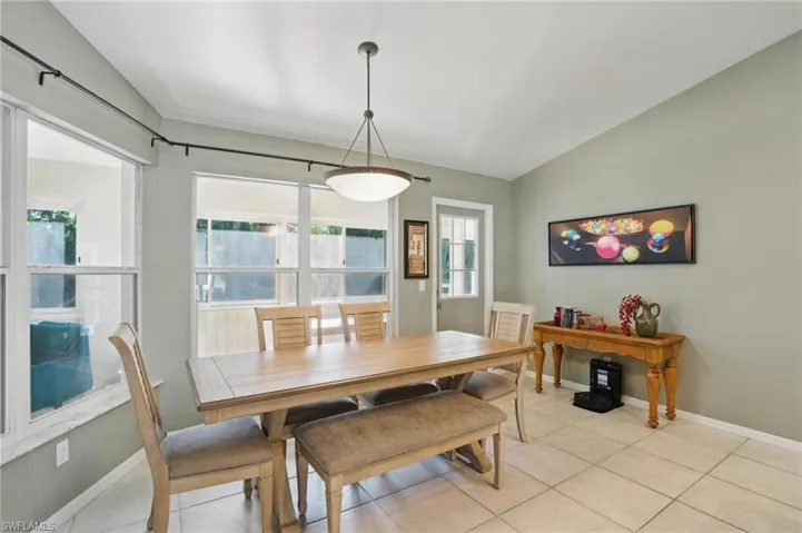 Dining space featuring baseboards, lofted ceiling, and light tile patterned flooring