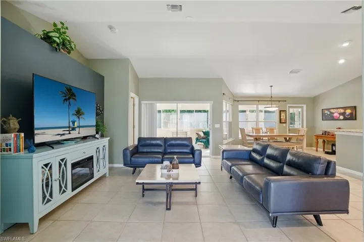 Living area featuring light tile patterned flooring, visible vents, baseboards, and lofted ceiling