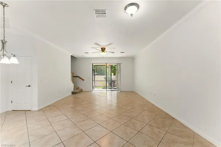 Unfurnished room with light tile patterned floors, stairs, a ceiling fan, crown molding, and baseboards