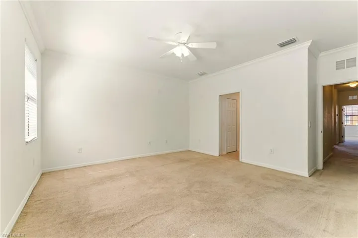 Unfurnished room with light carpet, ornamental molding, ceiling fan, and baseboards