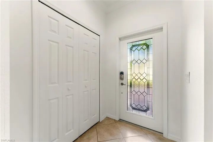 Foyer entrance with light tile patterned floors, crown molding, and baseboards