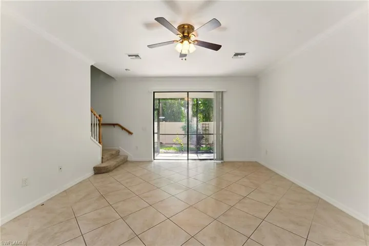 Spare room featuring crown molding, light tile patterned floors, stairs, ceiling fan, and baseboards