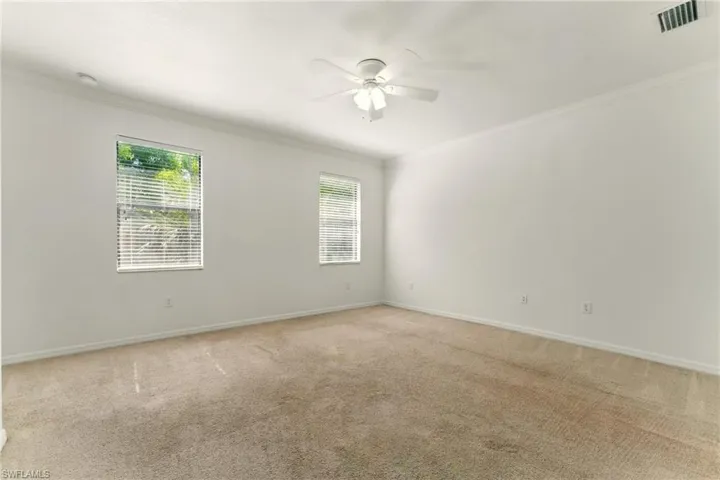 Spare room with crown molding, a ceiling fan, light colored carpet, baseboards, and a smoke detector