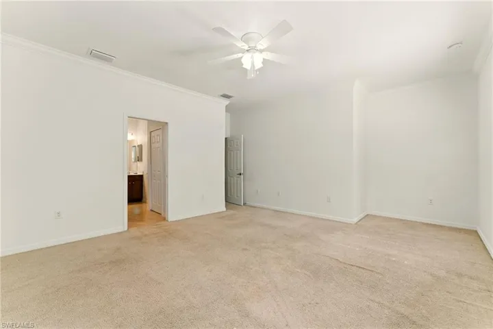 Empty room with crown molding, light carpet, ceiling fan, and baseboards