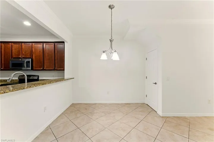 Kitchen featuring stainless steel appliances, crown molding, a chandelier, stone countertops, and pendant lighting