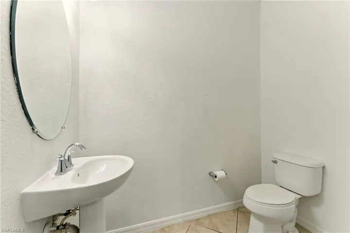 Bathroom featuring tile patterned flooring, toilet, baseboards, and a sink