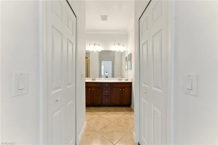Bathroom with double vanity, ornamental molding, tile patterned floors, a closet, and baseboards