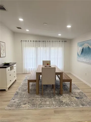 Dining space featuring light laminate finished floors, healthy amount of natural light, and recessed lighting