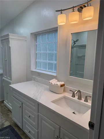 Bathroom with double vanity, a shower, and vaulted ceiling