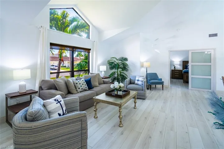 Living area with high vaulted ceiling and light wood-style floors