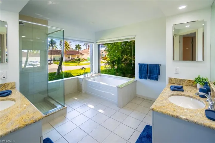 Full bath with two vanities, tile patterned flooring, a shower stall, a garden tub, and recessed lighting