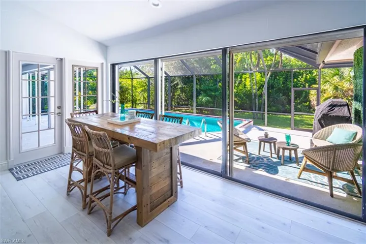 Dining room with lofted ceiling, a sunroom, light wood finished floors, and recessed lighting