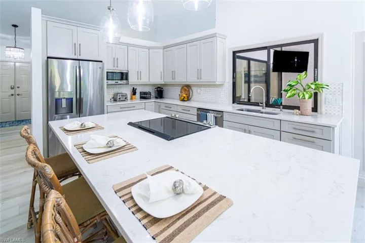 Kitchen with a kitchen island, tasteful backsplash, light wood-style flooring, a kitchen breakfast bar, and decorative light fixtures
